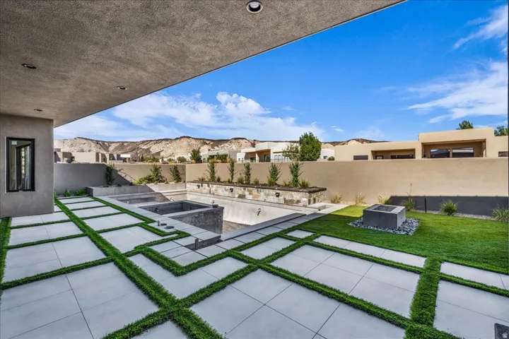 Expansive patio with integrated turf strips, an in-ground swimming pool, and an adjacent spa