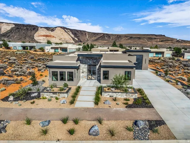 Contemporary stucco exterior with stone accents, a geometric entryway, a concrete driveway, and desert landscaping