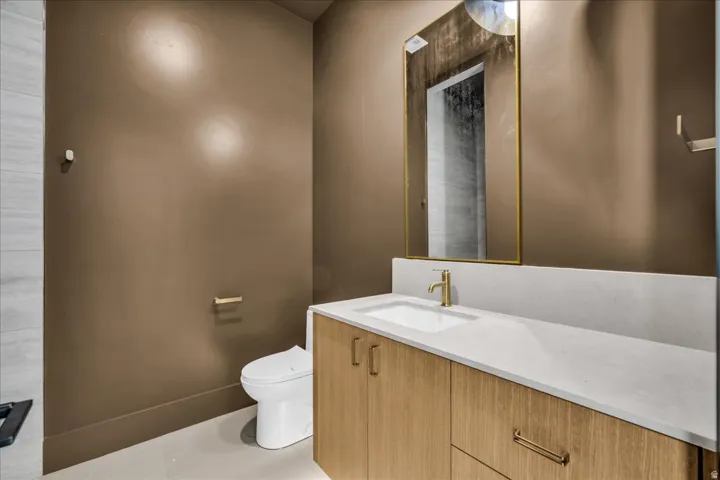Wood-finish vanity with an integrated sink, light-toned countertop, and a gold-toned faucet