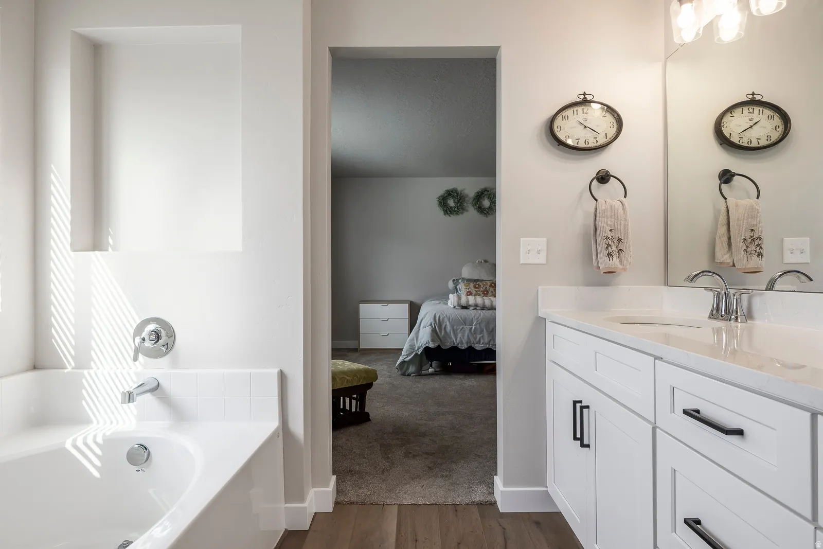 White vanity with black cabinet pulls, polished chrome faucet, and expansive mirror