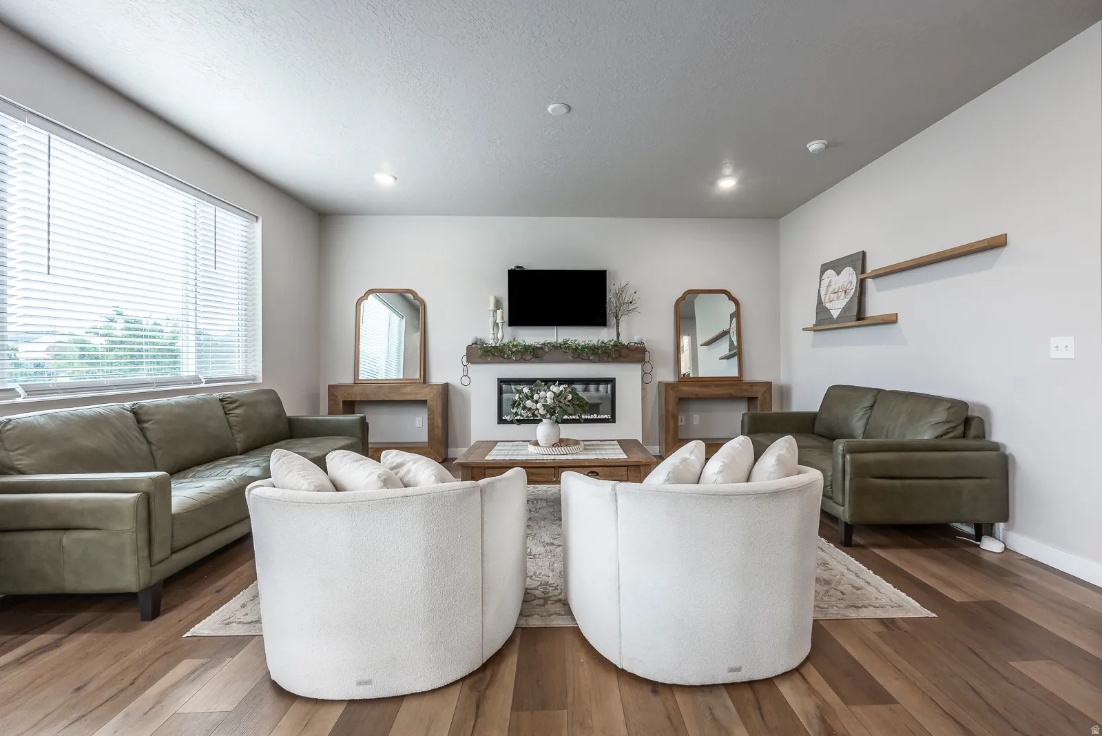 Spacious living area featuring wood-finish flooring, recessed lighting, and a built-in fireplace with a hearth