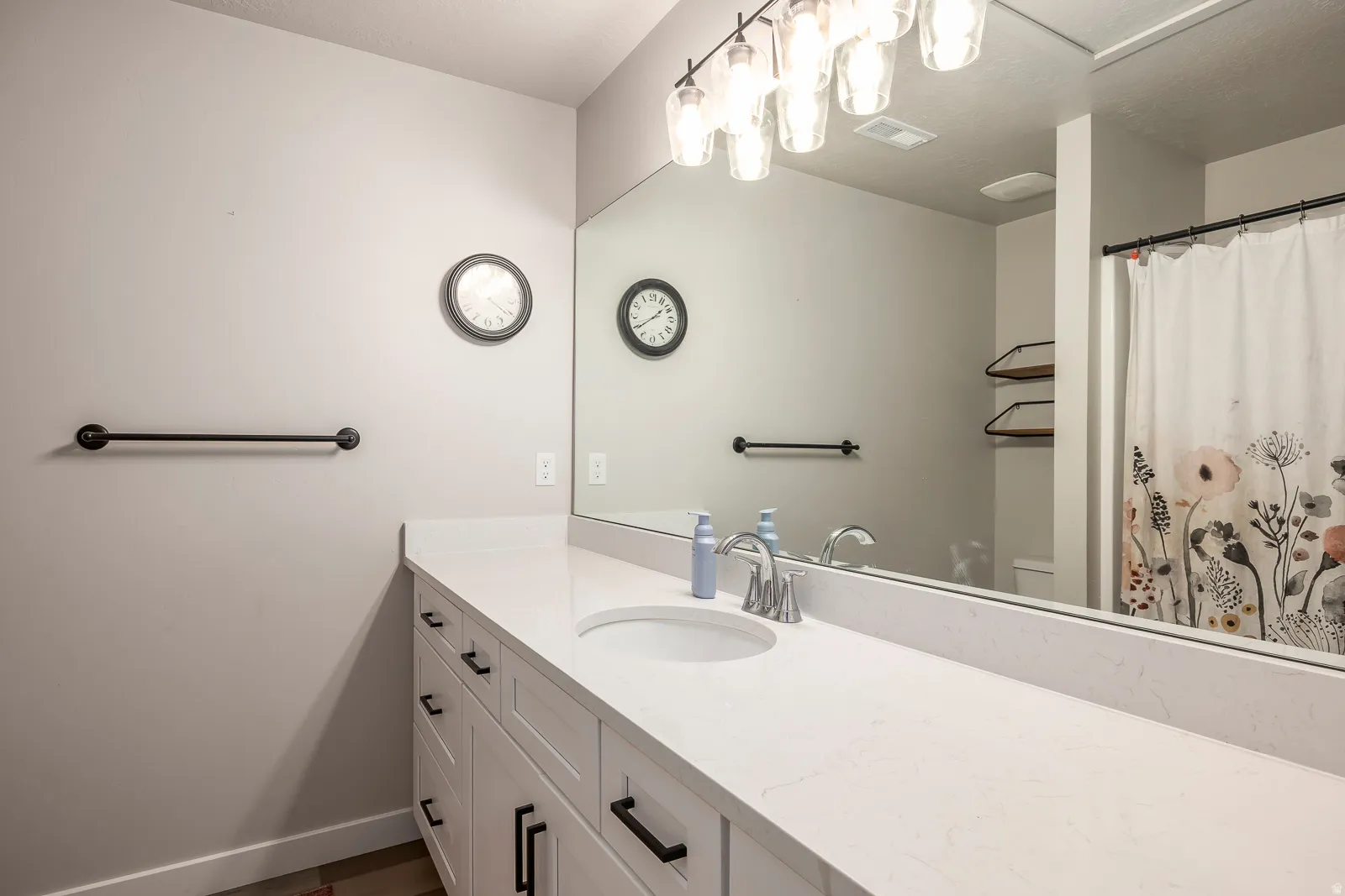 Vanity with white finish cabinetry, coordinating countertop, under-mount sink, and polished chrome faucet