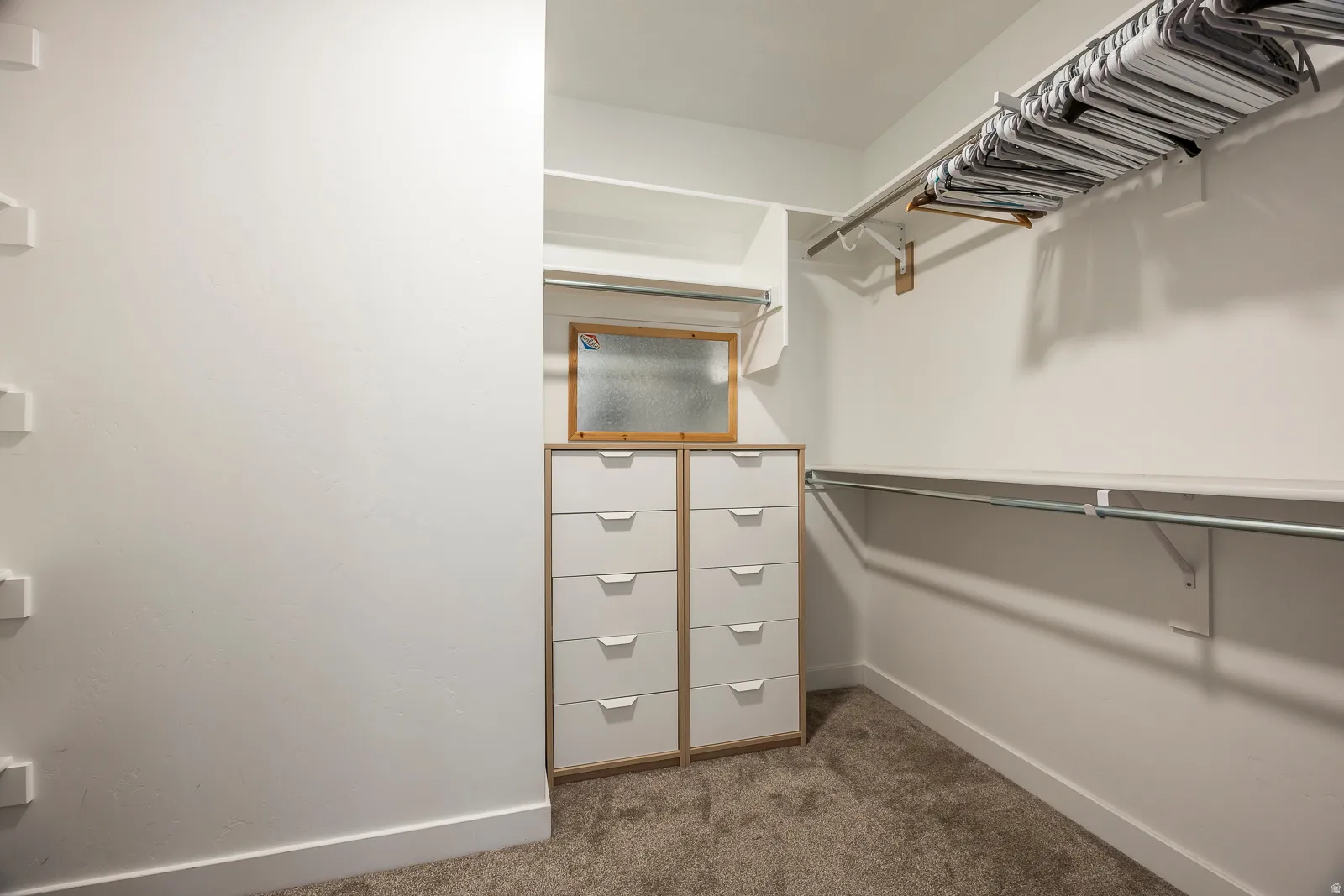 Built-in shelving, hanging rods, and integrated drawer storage with white drawer fronts and wood-finish framing