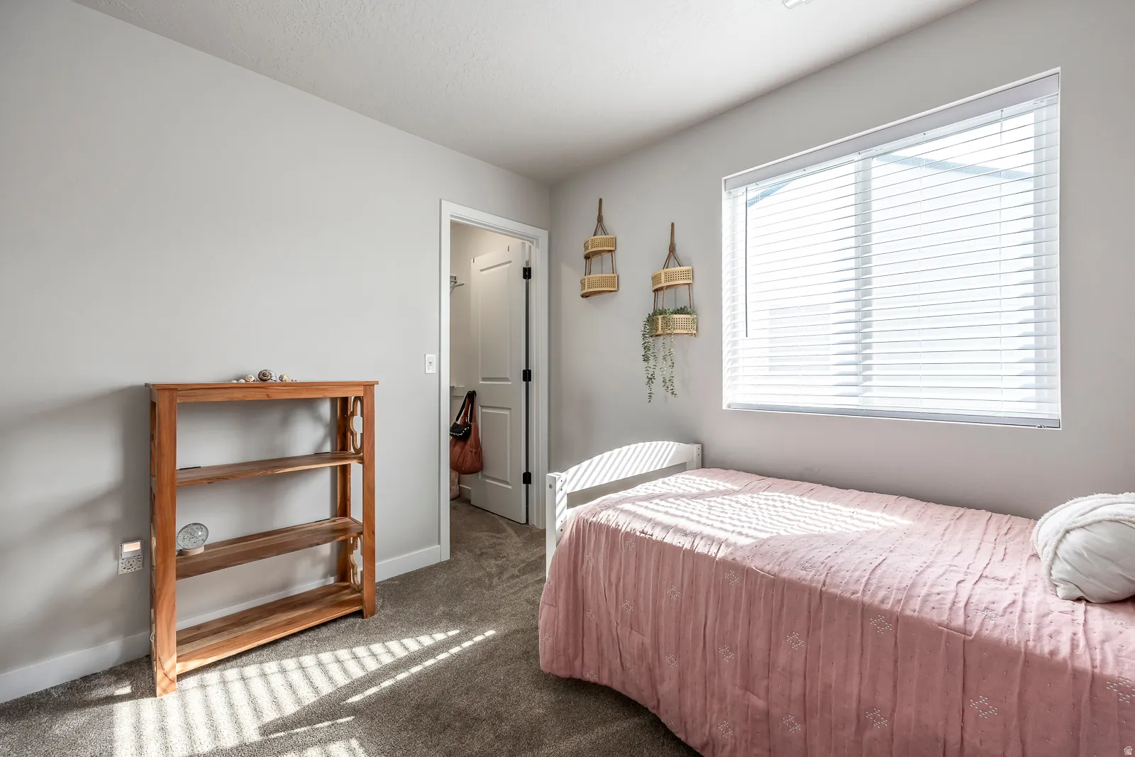Carpeted flooring, neutral wall tones, a window with blinds, and white trim