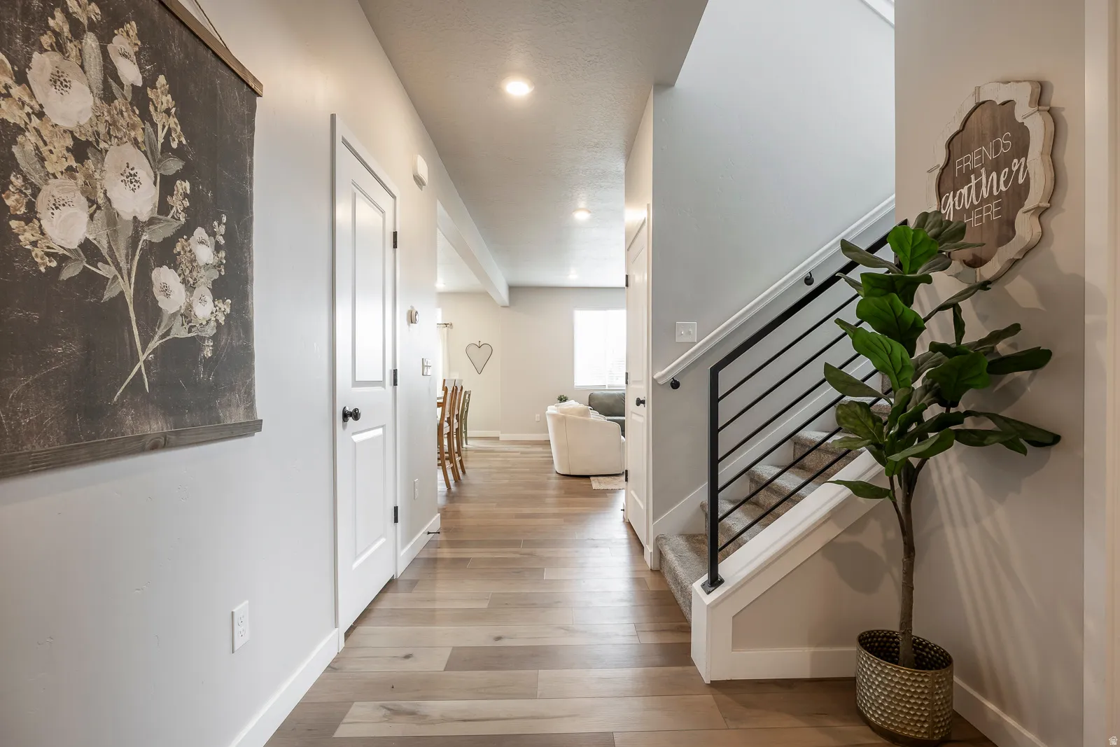 Wood-finish flooring throughout, bright recessed lighting, and a contemporary black metal stair railing