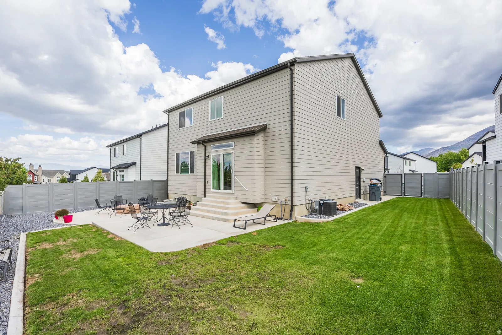 Expansive backyard featuring a manicured lawn, concrete patio, and privacy fencing