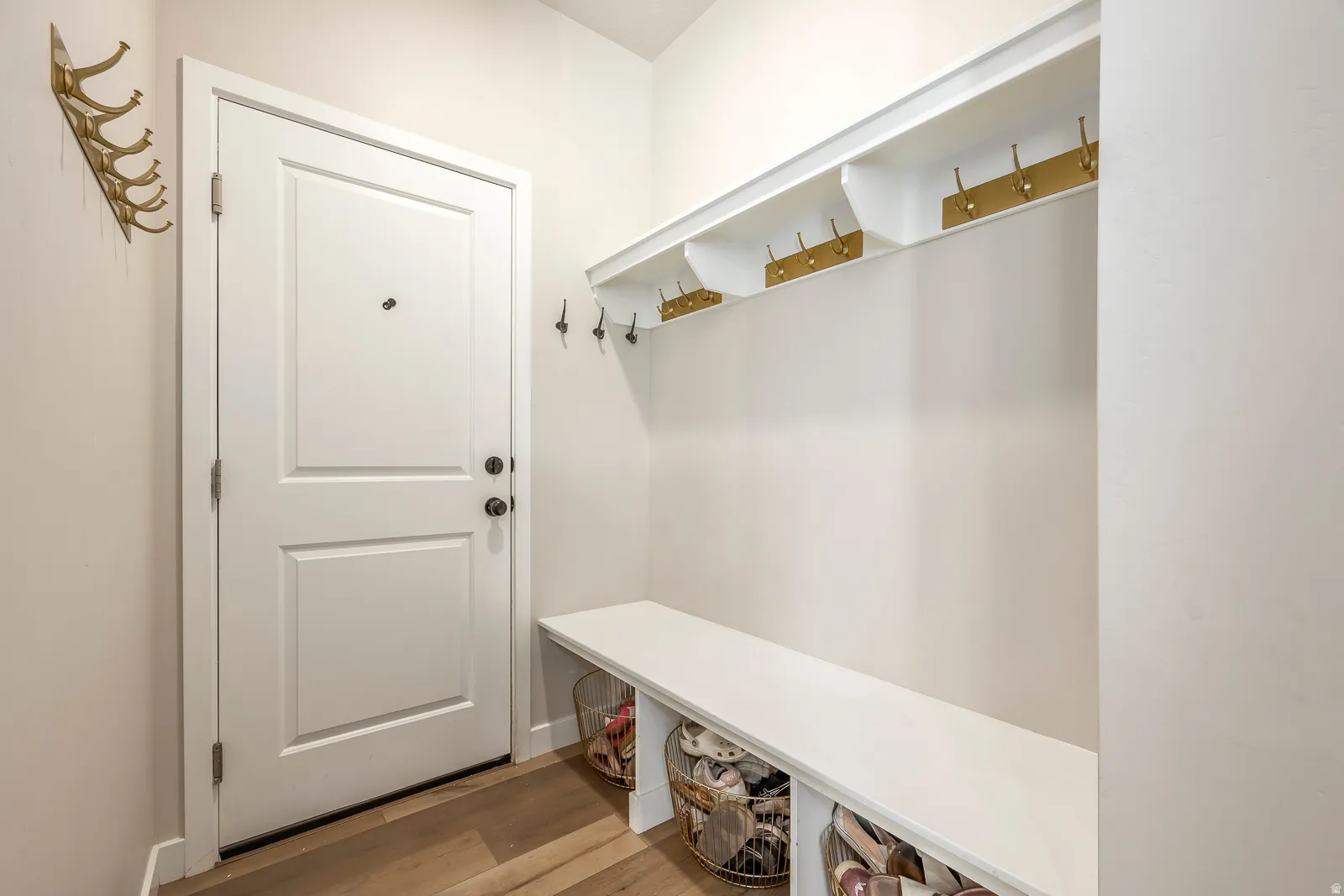 Built-in coat rack with integrated shelving, storage bench, and wood-finish flooring