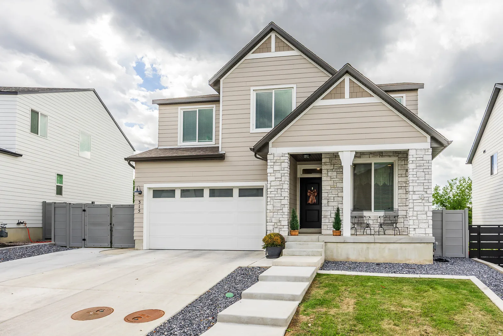 Two-story residence featuring a covered entry, stone column accents, and an attached garage