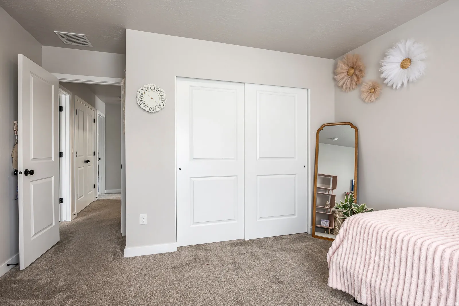Wall-to-wall carpeting, white sliding closet doors, and a solid white door with black hardware