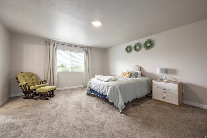 Plush carpeting, recessed lighting, and ample natural light from a window with blinds