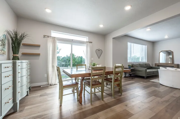 Recessed lighting throughout, wood-finish flooring, sliding glass door, white trim, and a wide interior opening