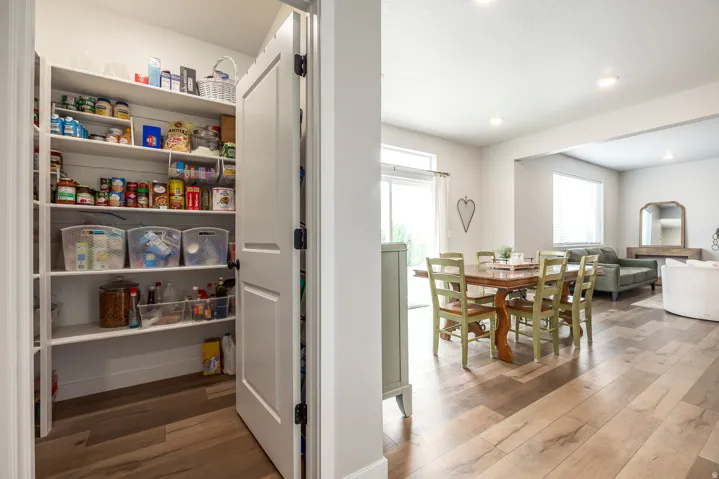 Spacious pantry with built-in shelving, wood-finish flooring, recessed lighting, and an open concept dining area