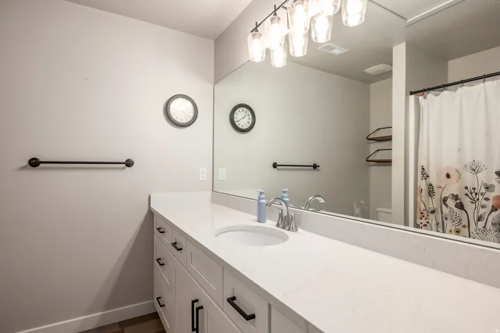 Vanity with white finish cabinetry, coordinating countertop, under-mount sink, and polished chrome faucet