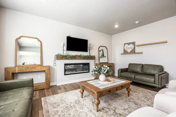Recessed lighting, wood-finish flooring, electric fireplace with a wood mantel, and floating shelves