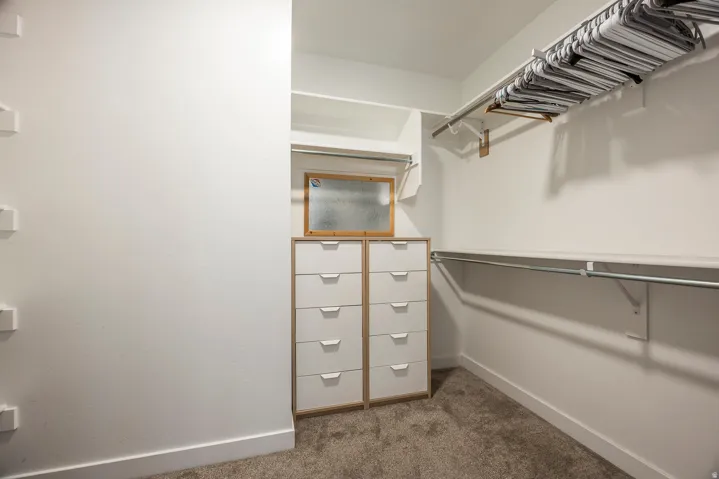 Built-in shelving, hanging rods, and integrated drawer storage with white drawer fronts and wood-finish framing