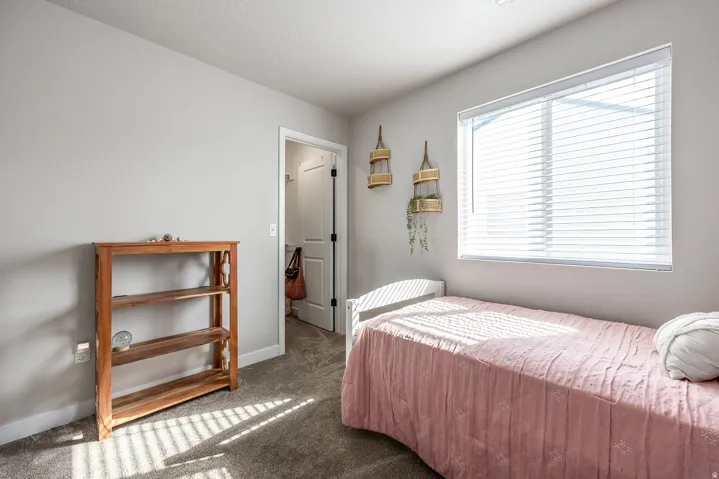 Carpeted flooring, neutral wall tones, a window with blinds, and white trim