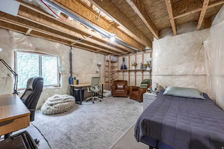 Unfinished basement offering exposed ceiling joists, wood-finish shelving, and an egress window