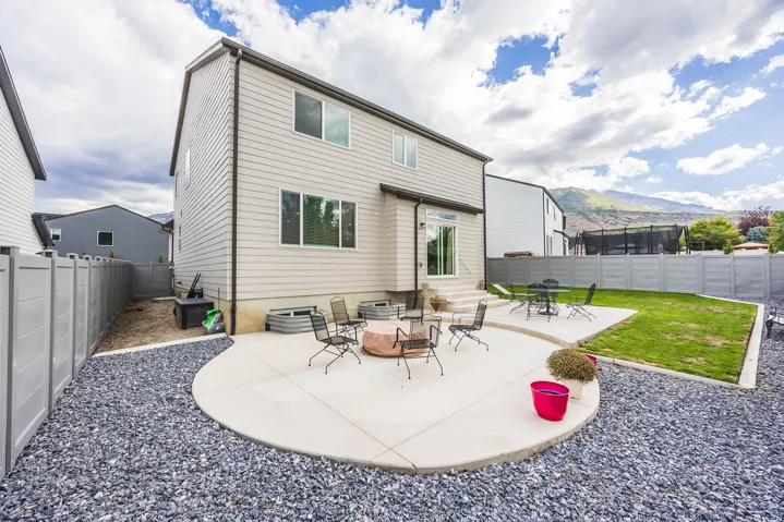 Expansive backyard featuring a concrete patio, gravel landscaping, and a manicured lawn