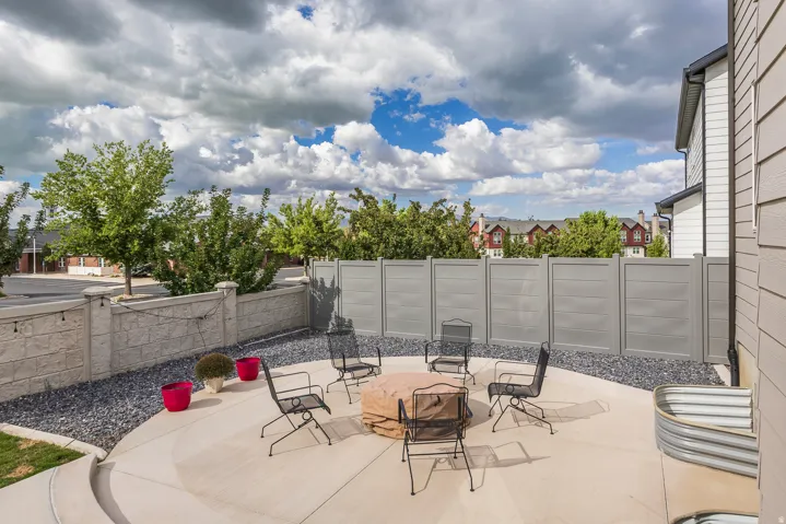 Spacious patio with a fire pit, concrete hardscaping, gravel landscaping, and a privacy fence