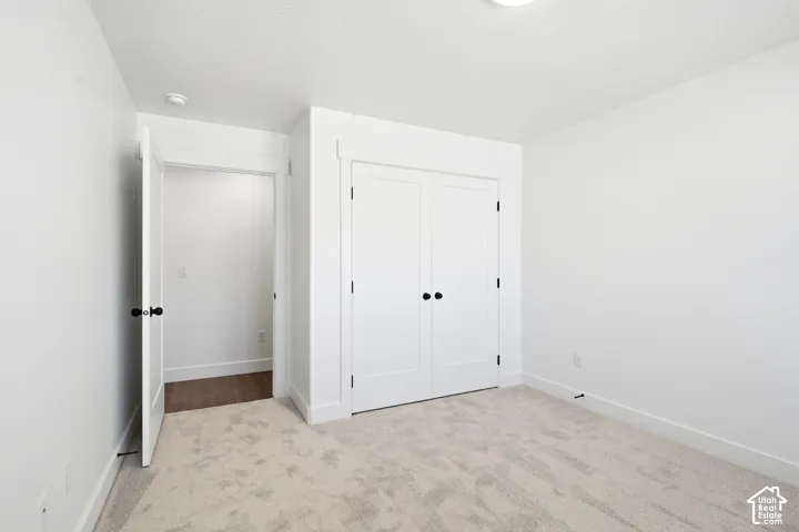 Plush carpet flooring, white walls, white trim, and a white bi-fold closet door