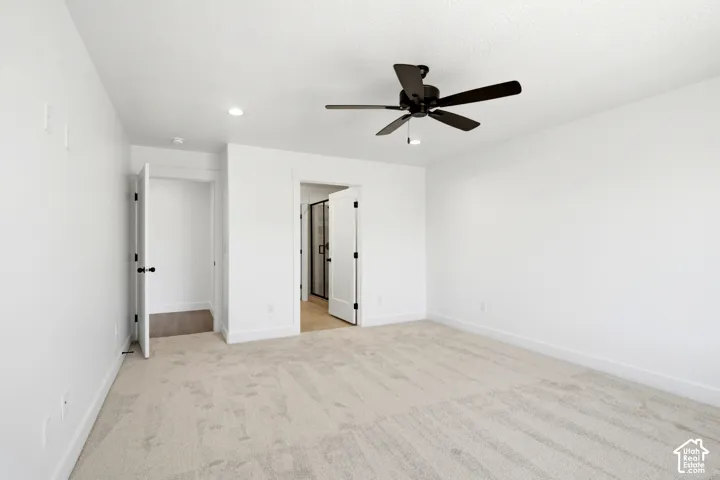 Spacious room with light-colored carpeting, a black ceiling fan, and recessed lighting
