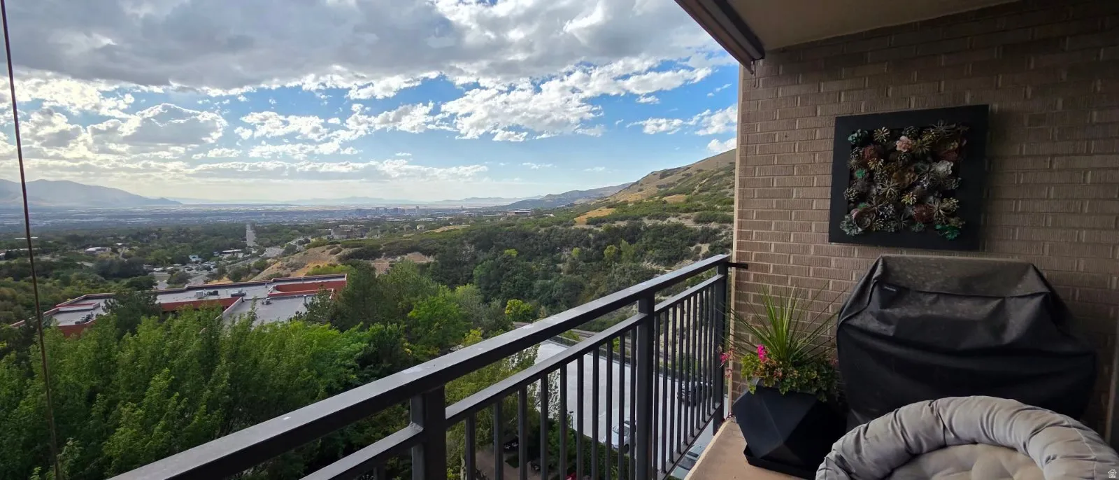 Balcony with black metal railing, offering expansive distant landscape and city scenery
