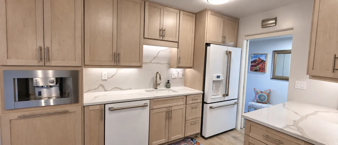 Kitchen featuring light wood-finish cabinetry, white countertops with veining, a built-in espresso machine, a large white refrigerator, and an undermount sink