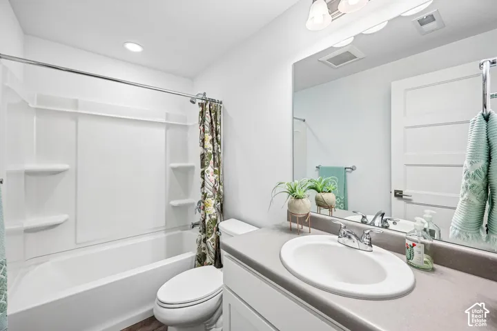 White bathroom featuring a built-in tub with a shower, a vanity with an integrated sink, a large mirror, and recessed lighting