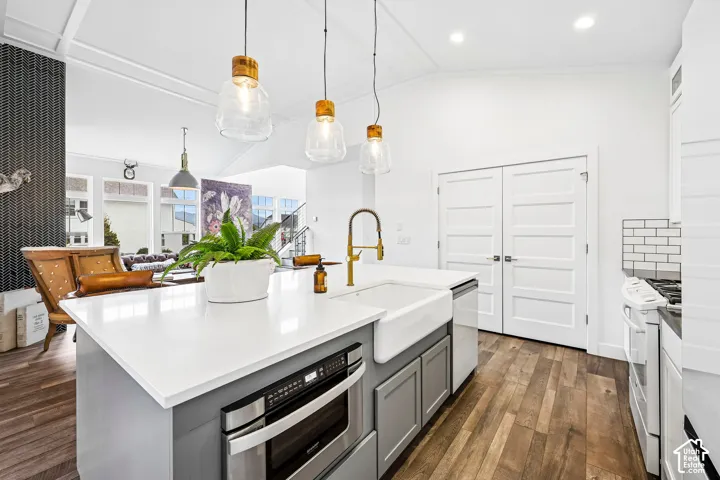 Kitchen island with a white quartz countertop, built-in drawer-style microwave, and farmhouse sink, dishwasher and custom bronze faucet.