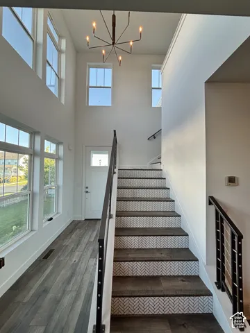 Two-story entry featuring a modern chandelier, laminate floor with tile risers and black metal railings