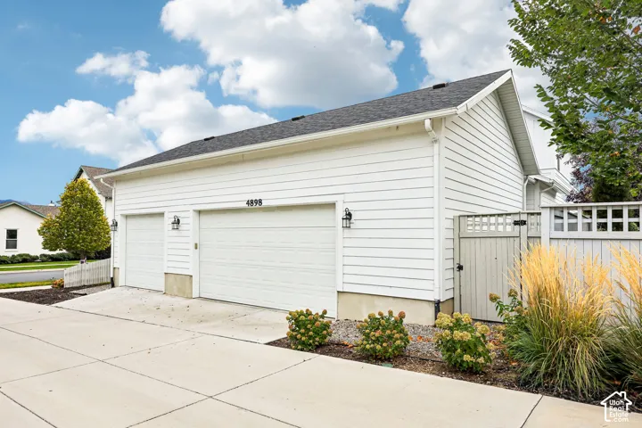 White horizontal siding exterior with a dark shingled roof, featuring a 3 car garage, and exterior light fixtures