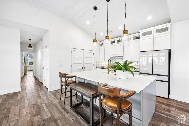Kitchen island with a white quartz countertops, extra cabinet/drawer storage in the island. Custom lighting, recessed llighting and custom bronze faucet, custom tile behind the stove.