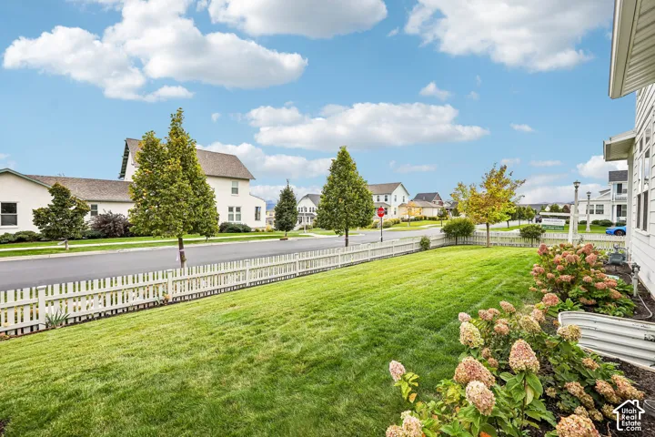 Expansive lawn area featuring a white picket fence and mature landscaping