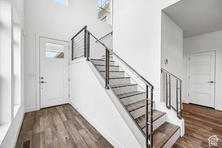 Impressive soaring entry with white walls, modern staircase with cable railing, transom window above the entry door, contemporary interior doors