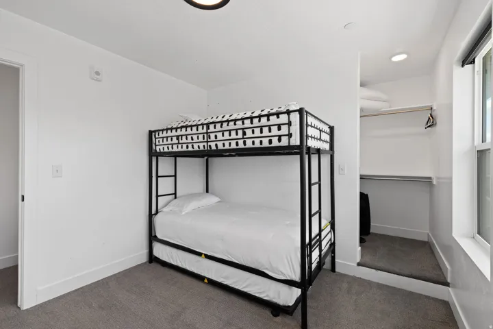 Carpeted room with white walls, a built-in closet with shelving and a hanging rod, and a window providing natural illumination