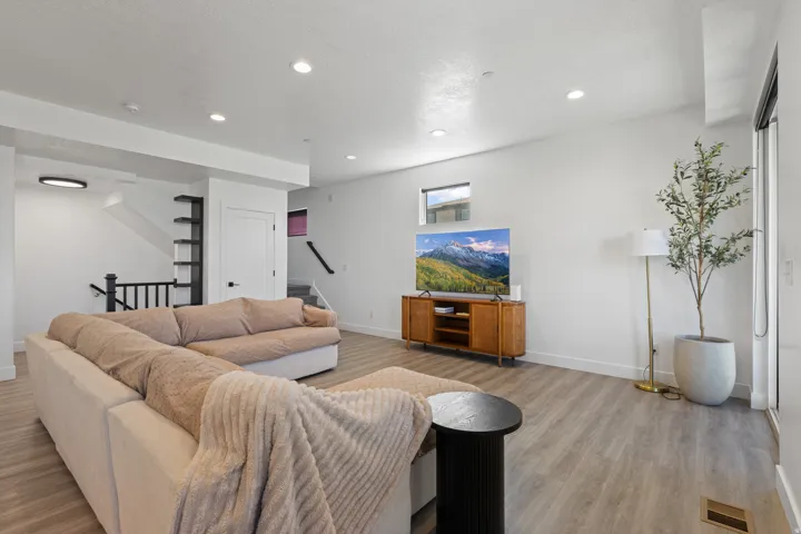Recessed ceiling lighting, wood-finish flooring, built-in shelving, white walls, and a sliding glass door