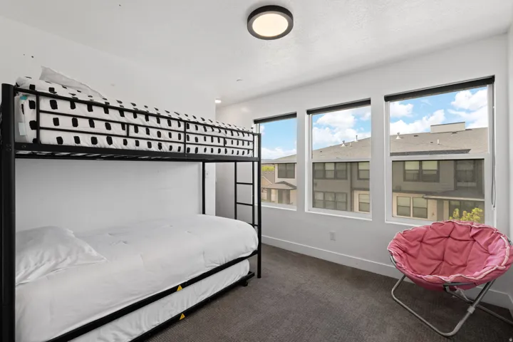 White walls with a textured carpet, featuring three large windows with window treatments, and a modern flush-mount ceiling light