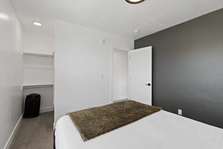 Recessed lighting, built-in closet shelving, accent wall, modern door hardware, and carpet flooring