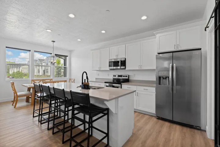 Open-concept kitchen with wood-finish flooring, white cabinetry, and stainless steel appliances