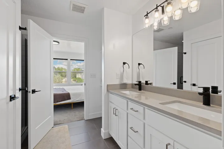 Dual vanity with integrated sinks, light-toned countertop, white cabinetry, and matte black fixtures