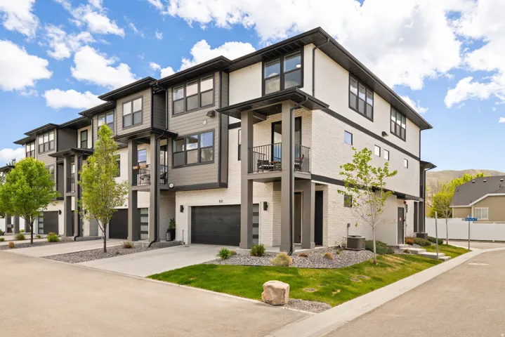 Contemporary multi-story exterior with dark trim accents, private balconies, individual garages, and concrete driveways