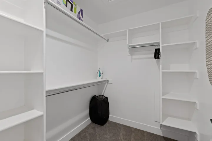 Built-in shelving, multiple hanging rods, and plush carpet flooring