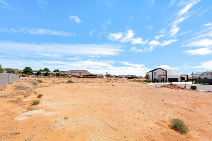 Expansive undeveloped lot with surrounding residential structures and distant mountain formations