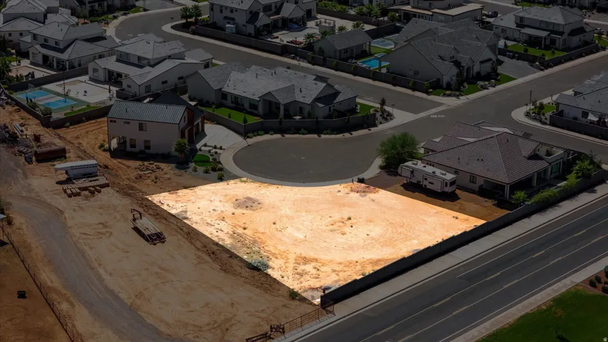 Expansive lot featuring a level terrain, bordered by a dark-toned fence, and surrounded by developed residential areas with paved roads