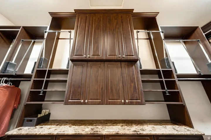 Built-in cabinetry with crown molding, integrated shelving, and pull-down clothing rods