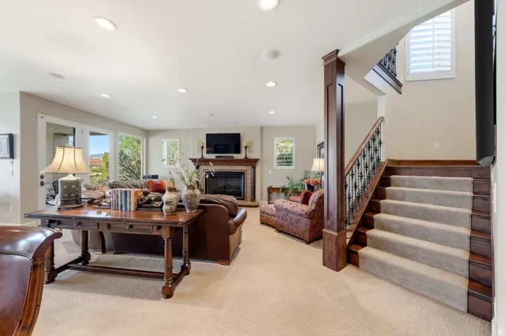 Recessed lighting throughout, fireplace with a mantel, French doors, wood-finish staircase with wrought iron balusters, and window shutters