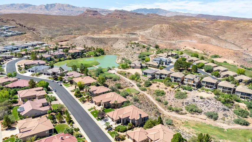 Residential development featuring a lake, surrounding desert landscape, and a paved road network