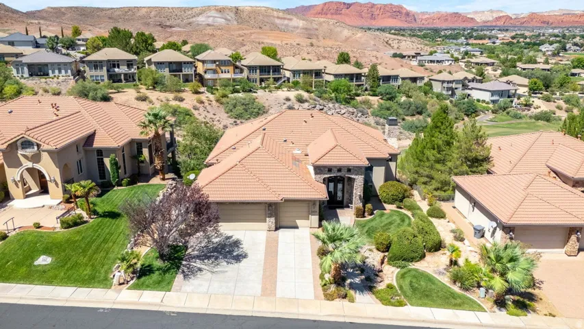 Tiled roofing, stucco exterior, two-car garage, mature landscaping, and a paved driveway