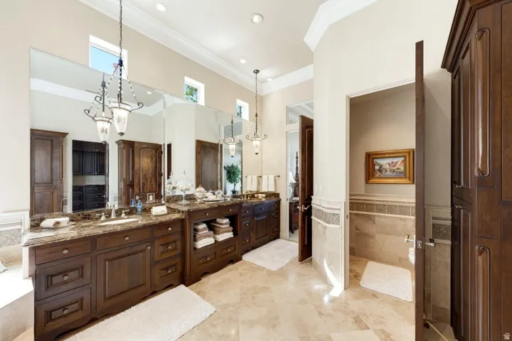 Dual wood-finish vanities with stone countertops, integrated sinks, and pendant lighting