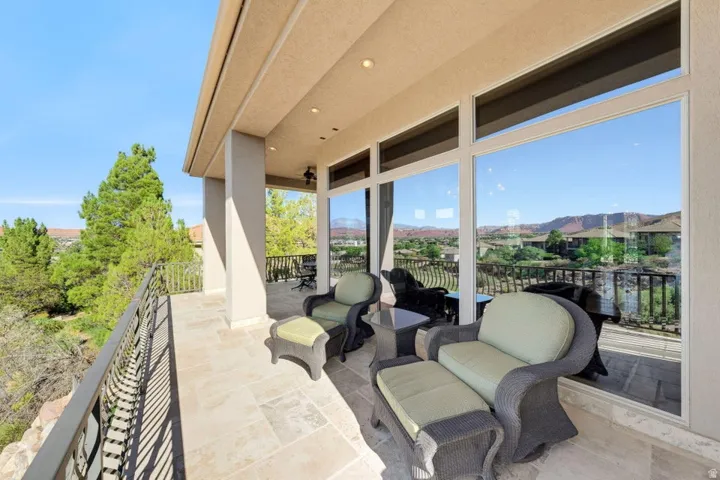 Expansive patio featuring tiled flooring, a decorative metal railing, a covered overhang, and large glass windows